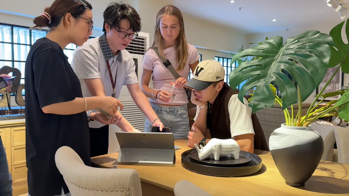A small group reviews materials and a laptop around a display table.