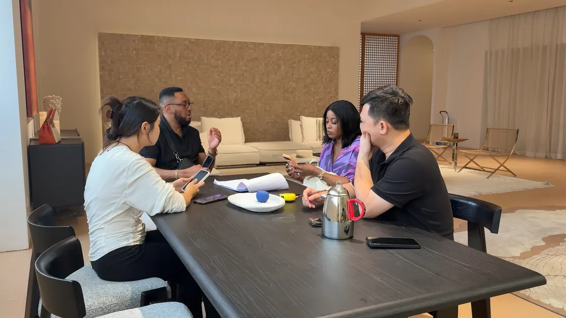 Four adults sit around a dark table with papers and phones.