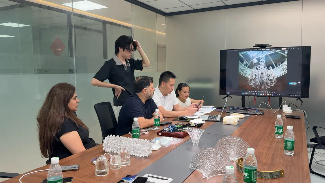 Five people gather around a table with a large chandelier reference on a screen and loose decorative parts in front.