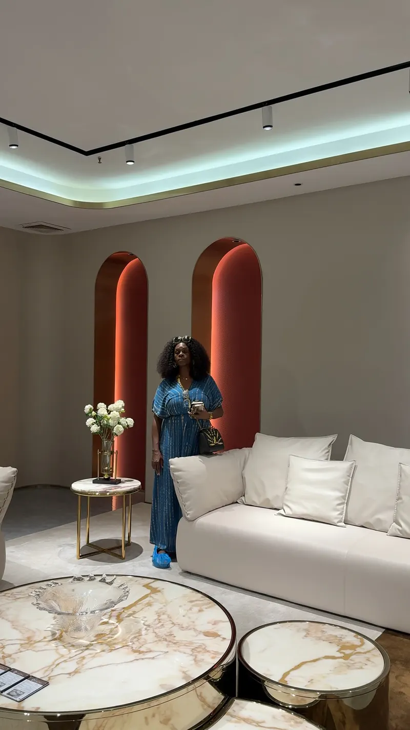 A person stands beside a light sofa and round low tables in a showroom.